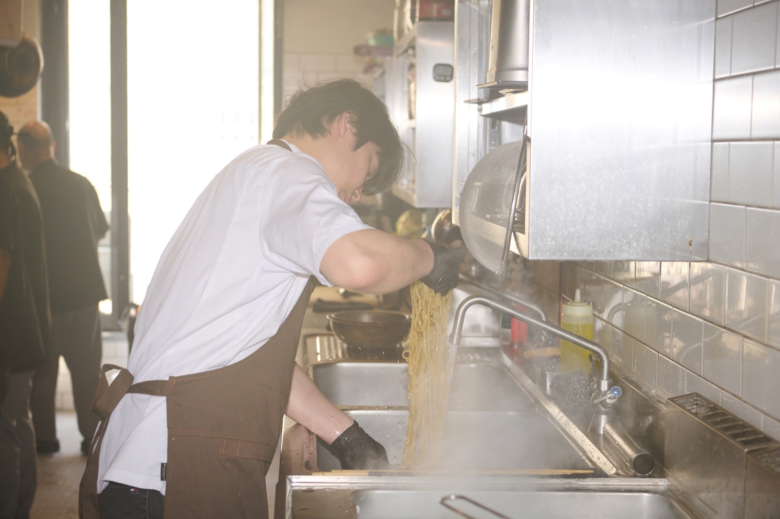 Un chef prépare des nouilles dans la cuisine d’un restaurant coréen à Paris